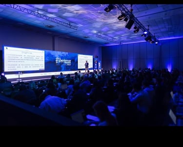 Um palco de evento, com varias pessoas assistindo
