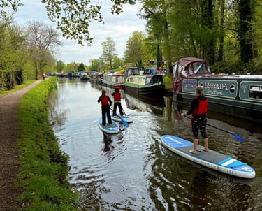 A family including two children paddle on the Monmouthshire and Brecon canal on SUP's hired from Bridge 76 Adventures.