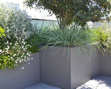 terrasse ou balcon aménagé avec des bacs contenant des arbustes, graminées et plantes fleuries
