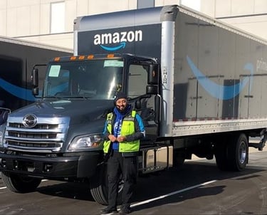 a man in a yellow vest standing next to an amazon truck