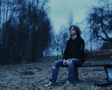 a man sitting on a bench in a park in a blue hour