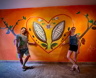 Man and woman standing near cacao mural at Reina's Chocolate in Costa Rica