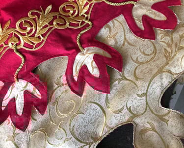 Photo de détails d'une tenue rouge et dorée avec des motifs dits de feuilles de chêne