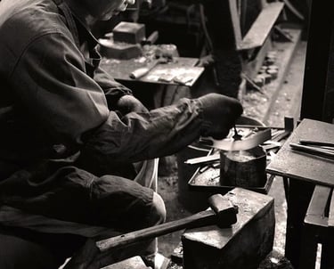 Historische Schwarzweißaufnahme eines japanischen Messerschmieds in einer traditionellen Schmiede in