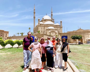 un grupo de turistas de pie frente a una mezquita de mohamed ali el cairo islámico