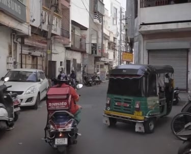 a zomato rider riding a motorcycle down an indian street