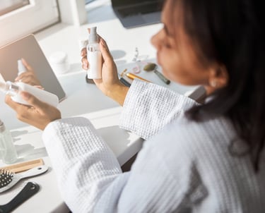 a woman in a bathrobe with a brush and products