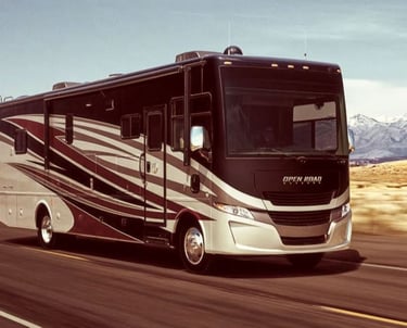 Tiffin Open Road Allegro Class A motorhome traveling on a scenic highway with mountains.