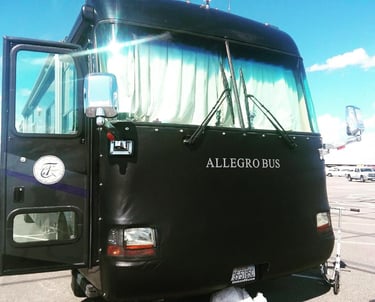 Front view of a black Tiffin Allegro Bus luxury motorhome with a protective leather bra cover.