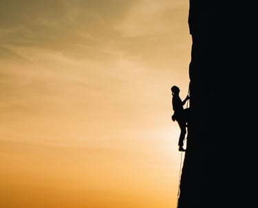 Giovane che scala una montagna al tramonto, simbolo di crescita personale per giovani e motivazione