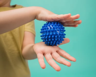a child's hand holding a blue ball