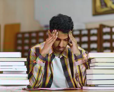 a man sitting at a table with a pile of books