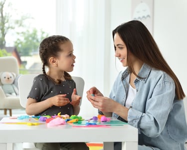 a woman sitting at a table with a little girl