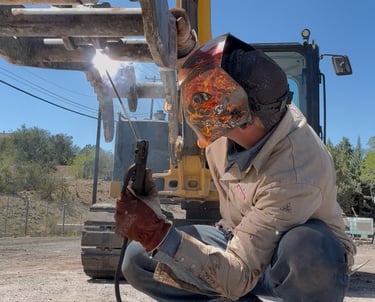 a man in a welding helmet welding a piece of equipment
