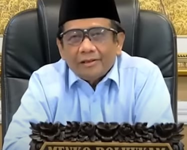 a man in a blue shirt and glasses sitting at a desk