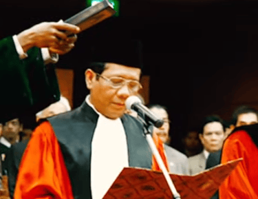 a man in a suit and tie is holding a microphone