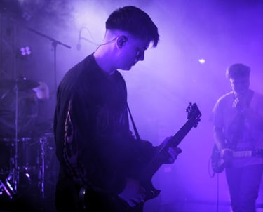 junger Musiker spielt bei Rock am alten Klärwerk auf einer Bühne.