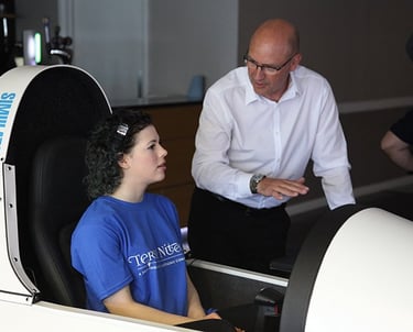 a lady in a simulator and a man