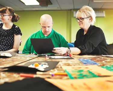 a man and woman sitting at a table with a laptop