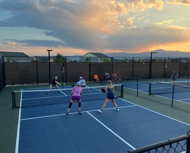 Adults playing competitive pickleball on outdoor courts during a pickleball coaching session.