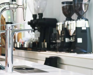 Barril de cerveza con cafeteras al fondo