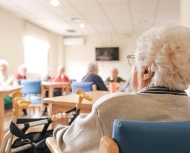 Una señora mayor está sentada a una mesa en un hogar de ancianos.