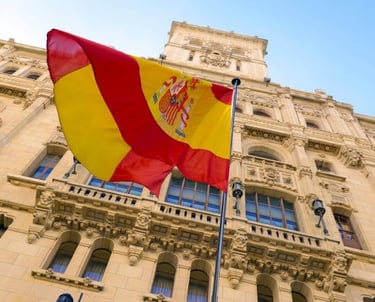 Bandera española ondeando frente a un edificio de oficinas