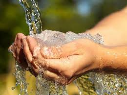 Fresh clean water splashing into cupped hands outdoors in natural sunlight.