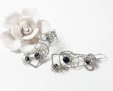 Earrings of steel wire handshaped in oblong with blue goldstone nestled with curls