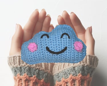 a person holding a crochet shaped like a cloud