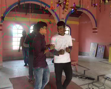 two men standing in a room with a pink wall
