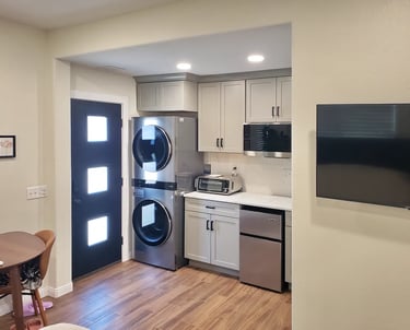Black door in kitchenette with light blue cabinets and stainless steel appliances.