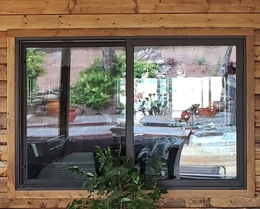 Bronze window with cabin style stained siding.