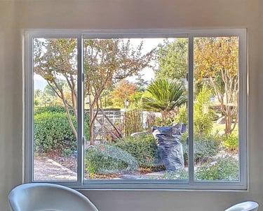 View of garden through white bay windows.
