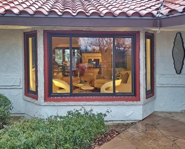 View of living room from outside a set of new Bronze bay windows.