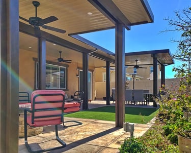 Large covered patio area with red chair, turf, and plants.