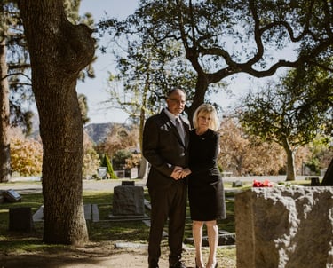 A couple in black in front of a grave