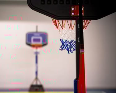 Canestro da basket nell'area multisport della palestra Move 2 Grow a Milano, con campo colorato sullo sfondo.