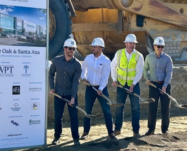 a group of people standing around a large sign ground breaking event planner