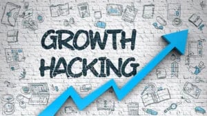 Growth Hacking" text on a brick wall surrounded by illustrations of various business icons, with a blue up arrow 