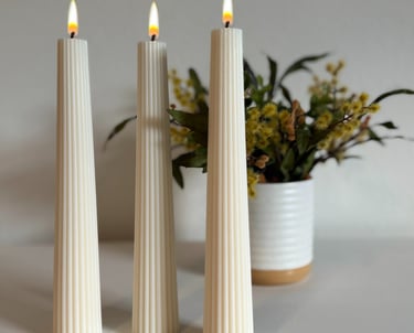 Three pillar candles lit and a flower vase