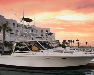 a boat in the water with a pink sky and buildings in the background