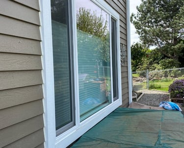 Exterior view of a house showing large sliding glass doors and siding.
