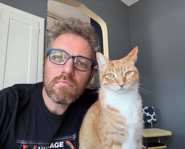 Photo of Hank with his ginger cat Pippin. They both have the same facial expression.
