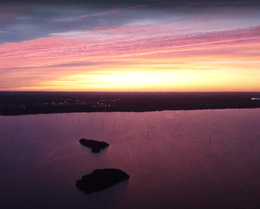 A breathtaking aerial view of a serene sunset over a large body of water.