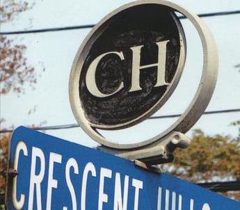 A Street sign of Crescent Hills Rd showing a logo mounted on top with the letters C H