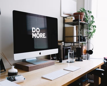 Organized desk and computer monitor with "do more." displayed on the screen