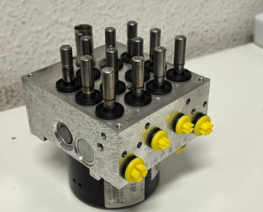 FOTO DESDE ARRIBA DE BOMBA HIDRAULICA DE ABS DESTAPADO Y RECIEN REPARADO CON TAPONES AMARILLOS DE CLAIRICAR EN LOS CANALES