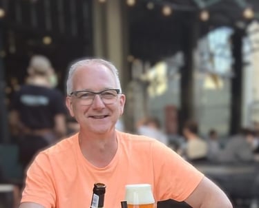 Portretfoto van Joop de Pooter die bij een restaurant een drankje drinkt
