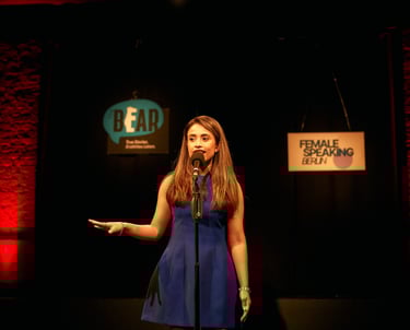 Confident woman speaking on stage, telling a story to an audience in a theatre